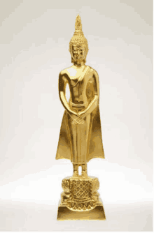 a gold statue of a buddha is standing on a white background