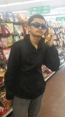 a young man wearing sunglasses and a black jacket stands in a store