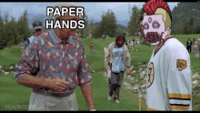 a man talking to another man on a golf course with the words paper hands above them