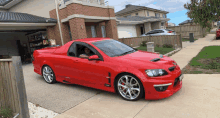 a red car is parked in a driveway in front of a house