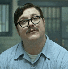 a man with glasses and a mustache is wearing a light blue shirt