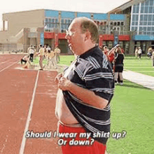 a man is standing on a track wearing his shirt up and down .