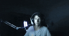 a man wearing headphones is sitting in front of a microphone in the dark .