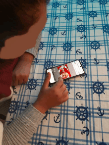 a person is using a cell phone on a table cloth with anchors and wheels