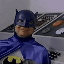 a man in a batman costume is smiling in front of a telephone .