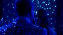 a man and woman are dancing in a dark room with blue lights behind them .