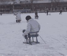 a person sitting in a chair on a snowy field with a sign that says ' beijing ' on it