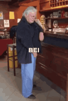 a man in a black jacket is standing in front of a counter with the word bei written on it