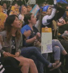 a group of people are sitting in a stadium and one of them is holding a sign that says ' transgender '