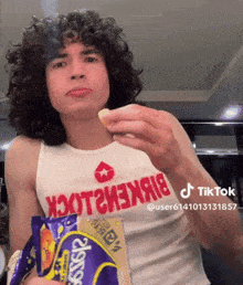 a man with curly hair is holding a bag of potato chips in his hand