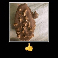 a close up of a chocolate bar with nuts on it and a thumbs up sign .