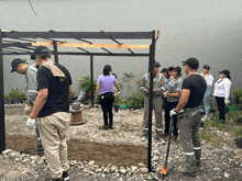 a group of people standing around a metal structure with a man wearing a black shirt that says ' a ' on the front