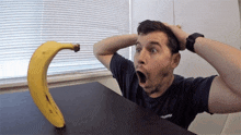 a man wearing a converse shirt is looking at a banana on a table