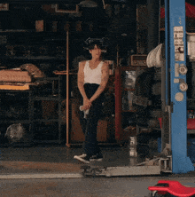 a man in a white tank top is standing in a garage with a sign that says ' fox ' on it