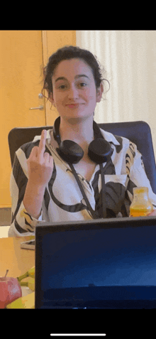 a woman wearing headphones is sitting at a desk giving the middle finger