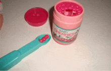 a pink container of baby cherry juice next to a blue toothbrush