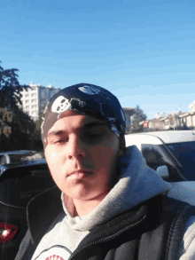 a man wearing a bandana with skulls on it looks at the camera