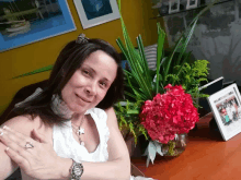 a woman wearing a watch is sitting in front of a vase of flowers