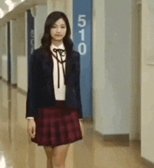 a woman in a school uniform is walking down a hallway .