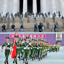 a group of soldiers marching in front of a building with chinese writing