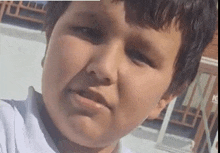 a close up of a young boy 's face with a serious expression .