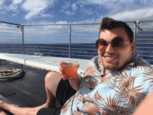 a man wearing sunglasses is sitting on a boat holding a glass