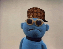 a blue stuffed animal with sunglasses and a hat on his head .