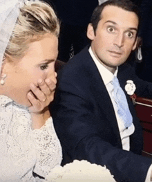 a bride and groom are sitting next to each other with the bride covering her mouth