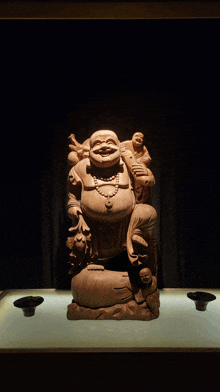 a wooden statue of a laughing buddha with a necklace around his neck