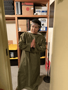 a man in a green robe stands in front of a cat6 box on a shelf