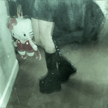 a person is holding a stuffed hello kitty doll