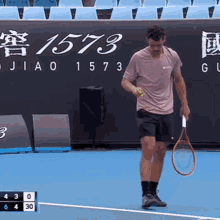 a man is holding a tennis racquet on a tennis court with a sign that says 1573 in the background