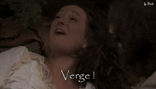 a woman is covering her mouth with her hands and the word verge is visible