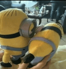 two stuffed minions are sitting next to each other in a living room .