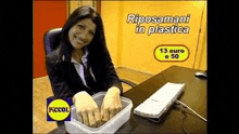 a woman is sitting at a desk with her hands in a container .