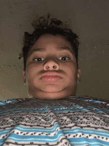 a young boy wearing a blue and white striped shirt makes a face