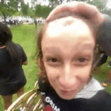 a woman is holding a brass instrument and making a funny face while standing in the grass .