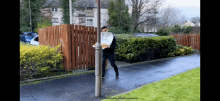 a man standing next to a pole holding a pizza