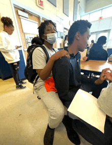 a girl wearing a face mask sits on a boy 's lap