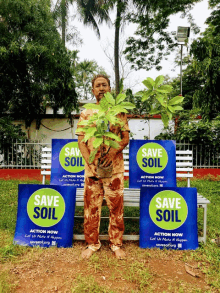 a man holding a plant stands in front of three signs that say save soil