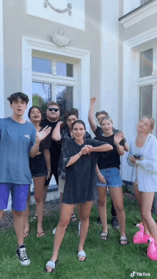 a group of young people are posing for a picture in front of a large building .