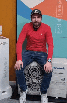 a man in a red shirt sits on a panasonic inverter