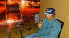 a man wearing a hat that says spurs sits in front of a grill