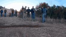 a group of people standing in a field with a man wearing a hoodie that says ' uc ' on the back