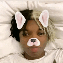 a young man with bunny ears on his face is laying on a bed .