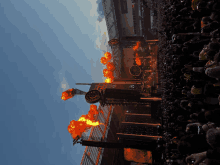 a crowd of people watching a stage with flames coming out