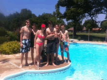 a group of people posing for a picture in front of a pool