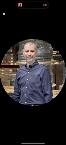 a man in a blue shirt stands in front of a warehouse