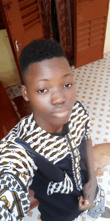 a young man taking a selfie in front of a door with a patterned shirt