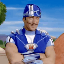 a man in a blue superhero costume with his arms crossed and a mustache .